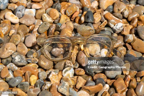 Pair of plastic spectacles glasses washed up on shingle beach, Shingle Street, Suffolk, England, UK,.