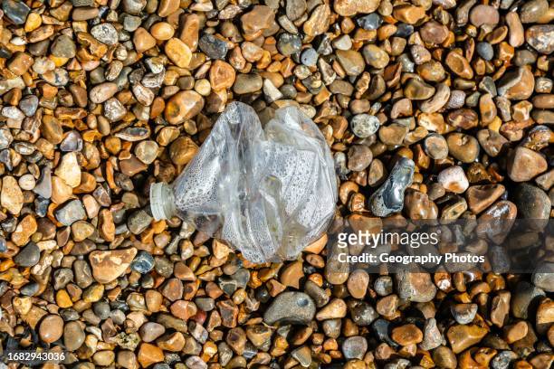 Crushed plastic bottle washed up on shingle beach, Shingle Street, Suffolk, England, UK,.