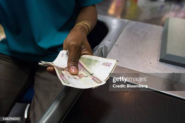 An employee holds Kenyan 1000 shilling notes at a cash desk inside the Nakumatt department store at Westgate Mall in Nairobi, Kenya, on Friday, May...