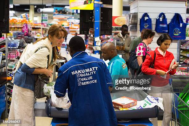 An employee, center, assists a customer at the cash desk inside the Nakumatt department store at Westgate Mall in Nairobi, Kenya, on Friday, May 3,...