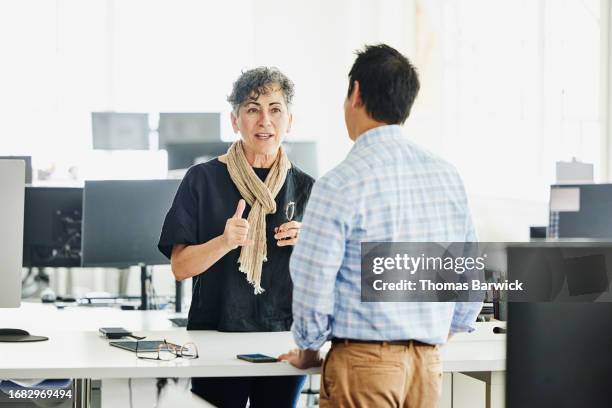 medium wide shot business owner discussing project with colleague in office - corporate business owner stock pictures, royalty-free photos & images