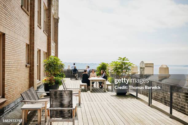 extreme wide shot coworkers meeting on rooftop deck of office building - rooftop deck stock pictures, royalty-free photos & images