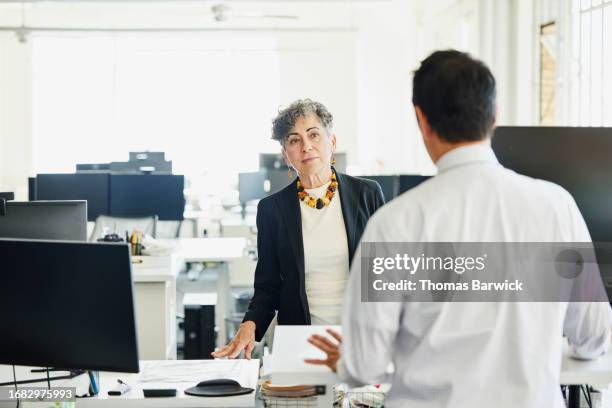 medium shot businesswoman in discussion at workstation in office - halbnahe-einstellung stock-fotos und bilder