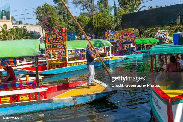 Popular tourist attraction people boating on colorful barges on canal at Xochimiloco, Mexico City, Mexico, trajinero punting barge.