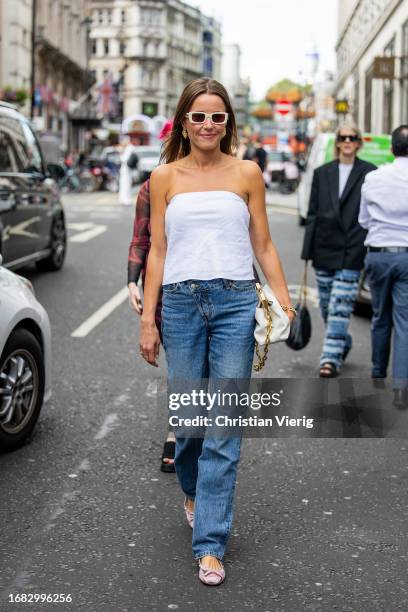 Chloe Street wears white off shoulder top, denim jeans, white bag, sunglasses outside Huishan Zhang during London Fashion Week September 2023 on...