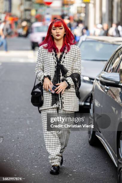 Guest wears checkered suit, black Prada bag outside Huishan Zhang during London Fashion Week September 2023 on September 15, 2023 in London, England.