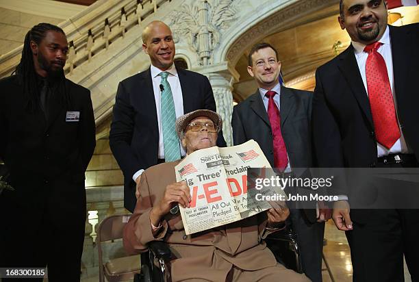 Ninety year-old WWII veteran Willie Wilkins shows a newspaper while standing with Newark Mayor Cory Booker on the 68th Victory in Europe Day at the...