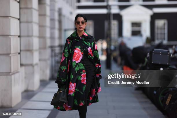 Tina Odjaghian seen wearing light rose colored Chloe cat eye sunnies, a black Richard Quinn Opera coat with floral rose prints in red and green, a...