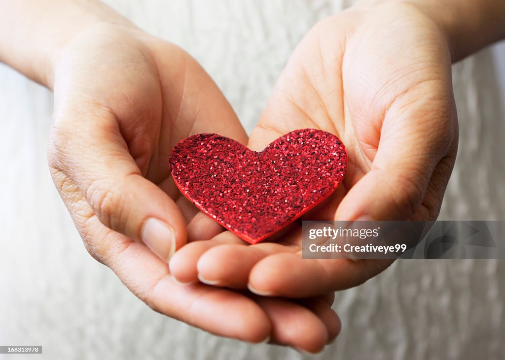 Hands holding a red heart.