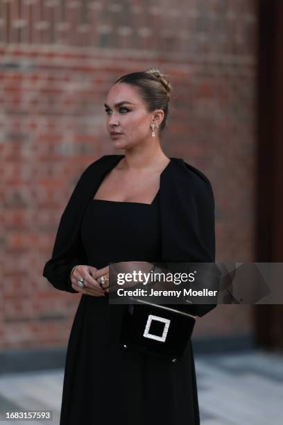 Nina Suess is seen outside the Jaeger LeCoultre cocktail party wearing diamond drop earrings, a black Zara dress with volant sleeves, a Jaeger...