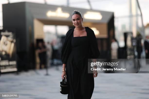 Nina Suess is seen outside the Jaeger LeCoultre cocktail party wearing diamond drop earrings, a black Zara dress with volant sleeves, a Jaeger...