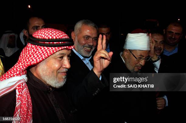 Hamas Prime Minister Ismail Haniyeh makes the V-Victory sign next to Egyptian Cleric and chairman of the International Union of Muslim Scholars...