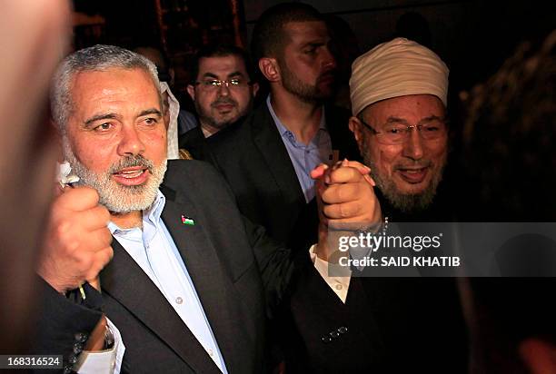 Hamas Prime Minister Ismail Haniyeh holds the hand of Egyptian Cleric and chairman of the International Union of Muslim Scholars Sheikh Yusuf...