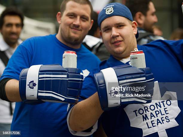 Jose Cripps, 26 and Justin Rodgers use their oversized, replica hockey glove, beer holders, as Maple Leaf fans gather in Maple Leaf Square prior to...