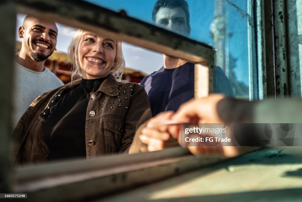Friends buying tickets at a ticket booth in the amusement park
