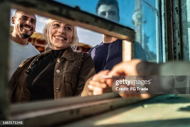 friends buying tickets at a ticket booth in the amusement park - amusement park ticket stock pictures, royalty-free photos & images