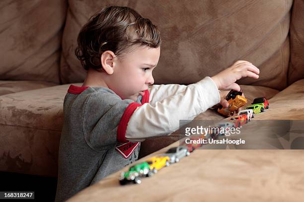 autistic boy playing with toy cars - ass stockfoto's en -beelden