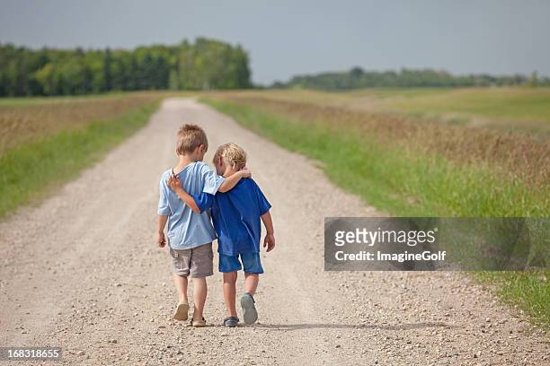 two caucasian boys walking down a country road - sharing stock pictures, royalty-free photos & images