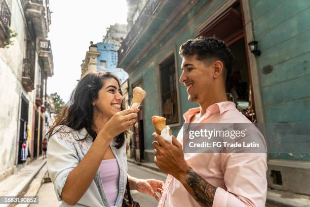 young couple talking while eating ice cream cone outdoors - cuban ethnicity stock pictures, royalty-free photos & images