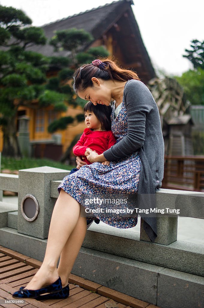 Young mom & toddler sitting in garden talking