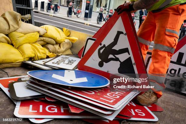 After temporary roadworks, a contractor sorts and stacks road signs and cones on the back of a lorry in the City of London, the capital's finanial...