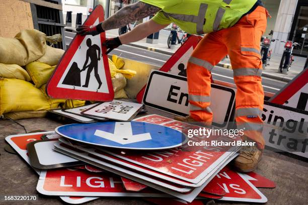 After temporary roadworks, a contractor sorts and stacks road signs and cones on the back of a lorry in the City of London, the capital's finanial...