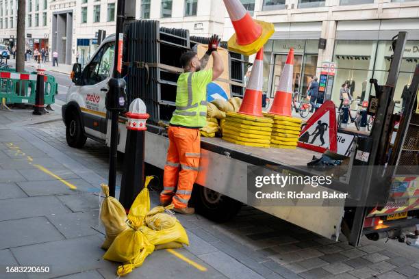 After temporary roadworks, a contractor sorts and stacks road signs and cones on the back of a lorry in the City of London, the capital's finanial...