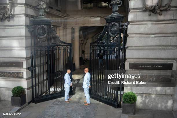 Two doormen wearing identical blue suits, stand at the open gates of Rosewood London in Holborn, on 22nd September 2023, in London, England. Rosewood...