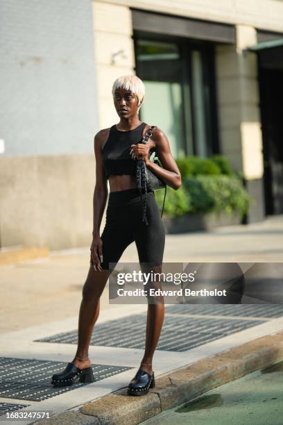 Guest wears a black crop tank top, a black leather bag, black short leggings, black leather studded sandals, outside Ndigo, during New York Fashion...