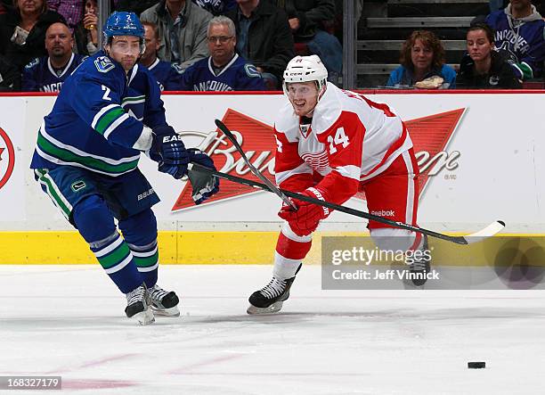 Dan Hamhuis of the Vancouver Canucks and Gustav Nyquist of the Detroit Red Wings battle for a loose puck during their NHL game at Rogers Arena April...