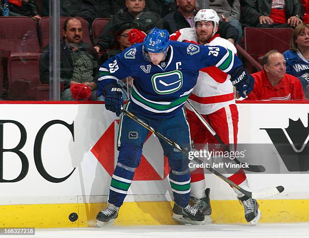 Henrik Sedin of the Vancouver Canucks and Henrik Zetterberg of the Detroit Red Wings battle along the boards for the puck during their NHL game at...