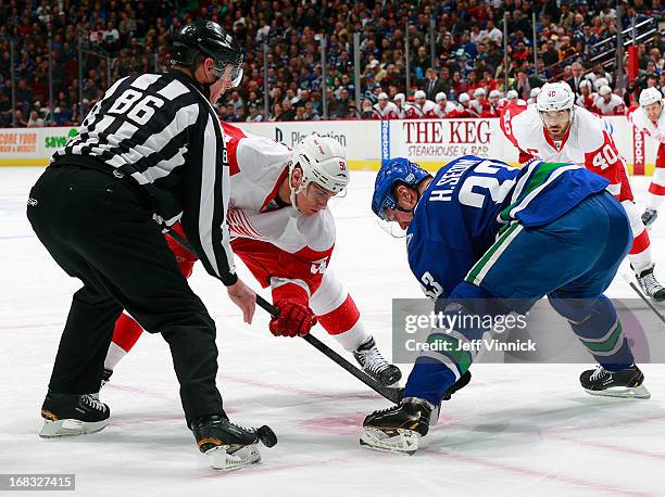 Linesman Brad Lazarowich drops the puck as Valtteri Filppula of the Detroit Red Wings and Henrik Sedin of the Vancouver Canucks face-off during their...