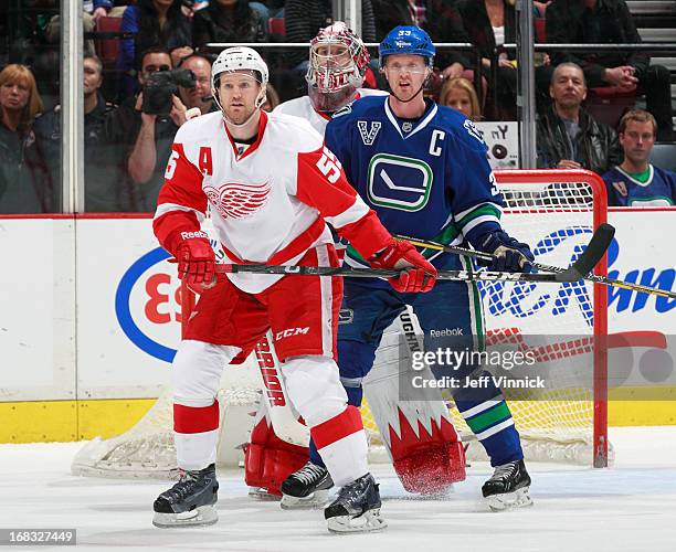 Henrik Sedin of the Vancouver Canucks ad Niklas Kronwall of the Detroit Red Wings stand in front of Jimmy Howard of the Detroit Red Wings during...