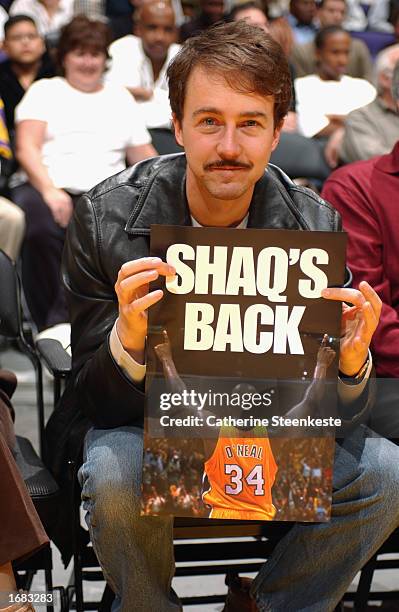 Actor Edward Norton sits courtside as he holds a poster announcing the return of center Shaquille O'Neal of the Los Angeles Lakers from a toe injury...