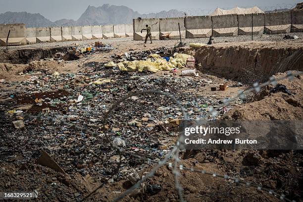 Soldier in the Afghan National Army walks past a burn pit at a command outpost recently handed over to the ANA from the United States Army on March...