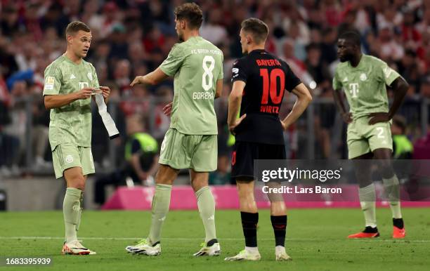Joshua Kimmich of Muenchen gives the captains armband to team mate Leon Gorezka during the Bundesliga match between FC Bayern München and Bayer 04...