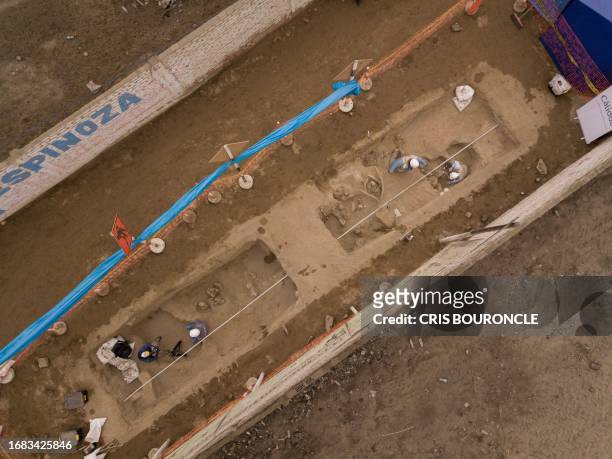 In this aerial view archaeologists recover ancient human remains and artifacts discovered by workers excavating a street in a rural area in the...