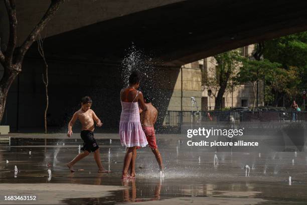 September 2023, Brazil, Sao Paulo: Children play at a fountain in the city. Due to the unusually high temperatures for this time of year, passers-by...