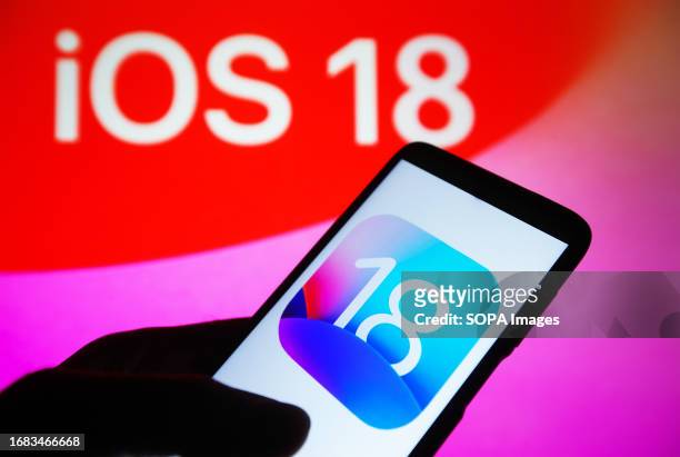 In this photo illustration, iOS 18 logo is seen on a smartphone and on a pc screen in the background.