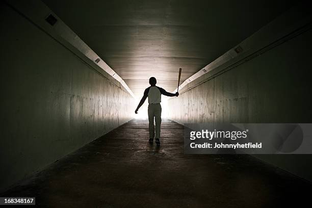 baseball player walking out of stadium tunnel swinging bat  - baseball sport stock pictures, royalty-free photos & images