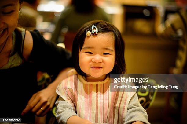 Toddler girl and young mom smiling on dining table