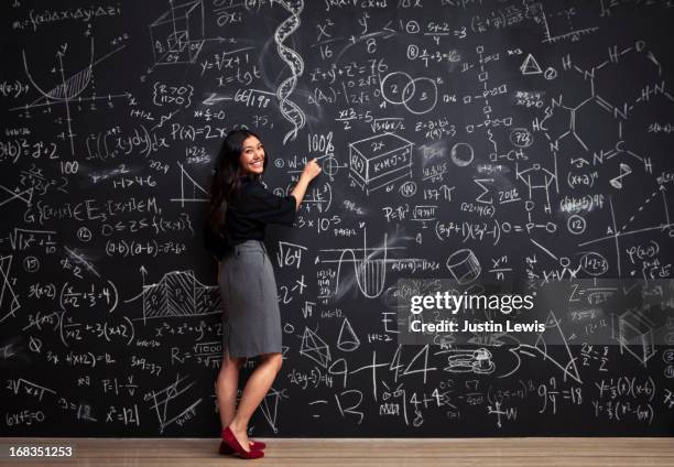 young woman writes math equations on chalkboard - blackboard women stock pictures, royalty-free photos & images