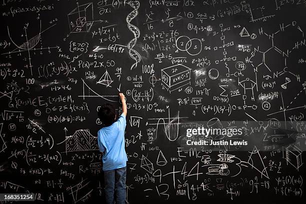 young boy writes math equations on chalkboard - mathematische formel stock-fotos und bilder