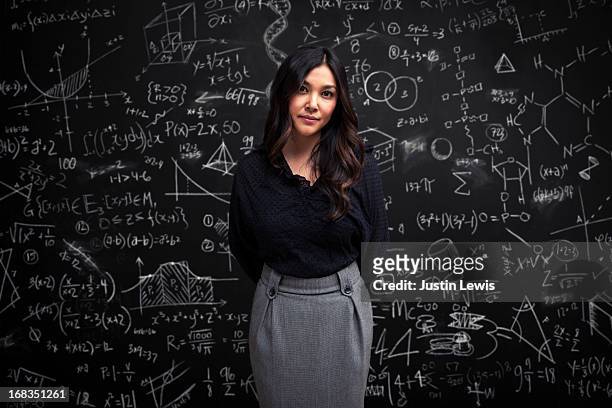 woman stands calm in front of math chalkboard - wisdom stock pictures, royalty-free photos & images