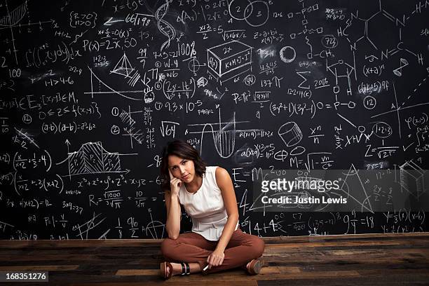 young girl sits by mathematical chalkboarda - formula fotografías e imágenes de stock