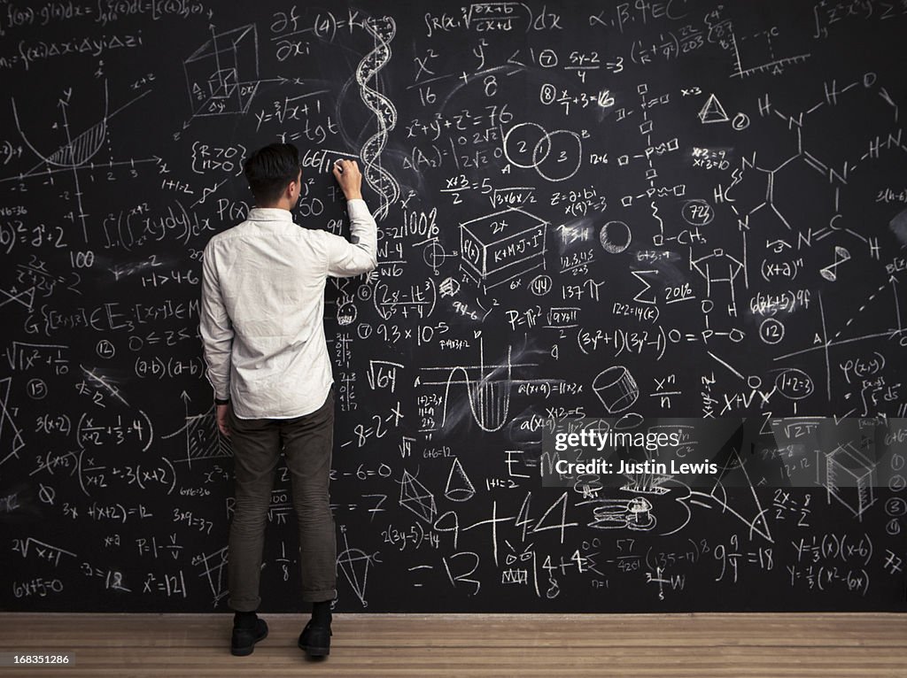 Man writes mathematical equations on chalkboard