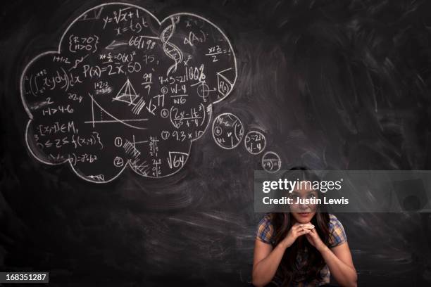 girl contemplates math thought bubble on chalkboar - simbolos matematicos fotografías e imágenes de stock