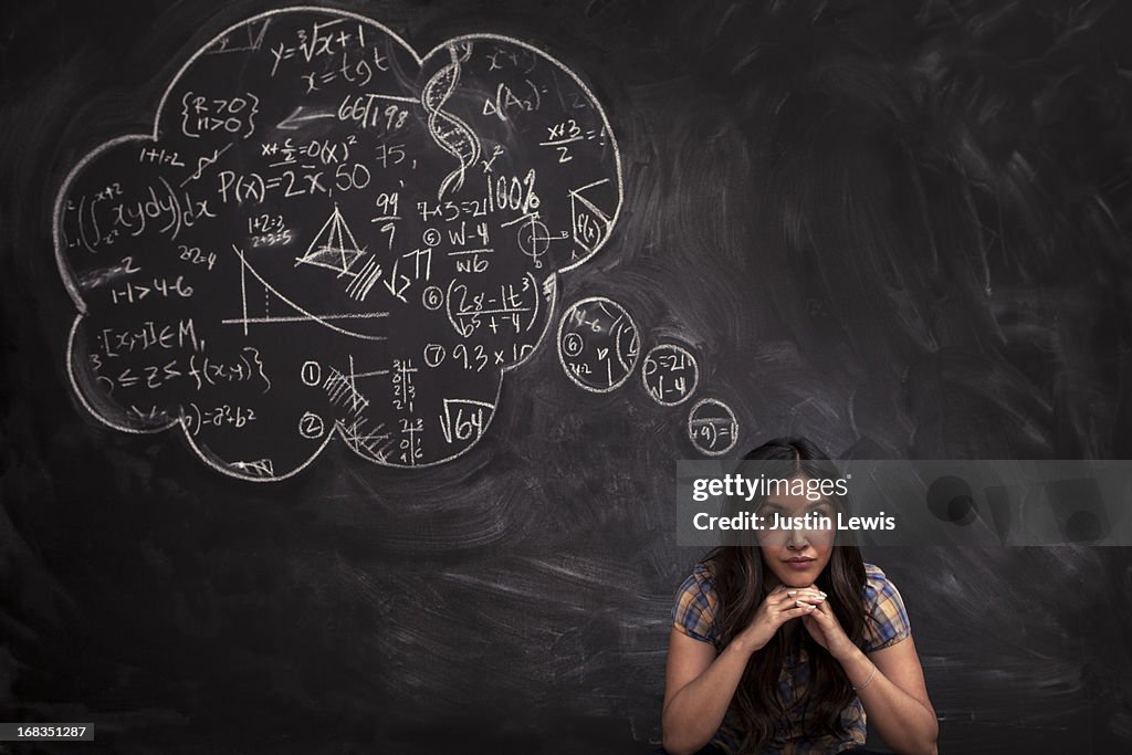 Girl contemplates math thought bubble on chalkboar