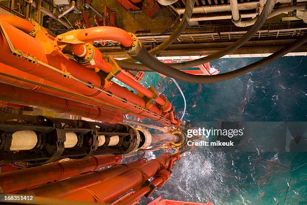 oil rig view riser pipes down to sea level - olie industrie stockfoto's en -beelden