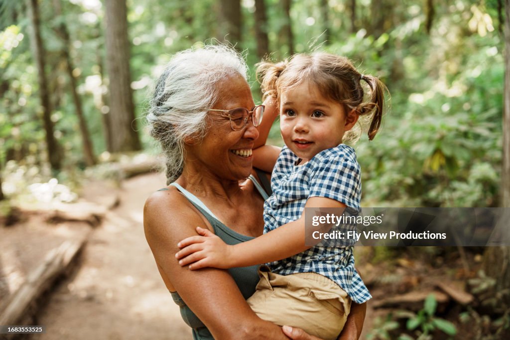 Vibrant Pacific Islander senior woman hiking with Eurasian granddaughter